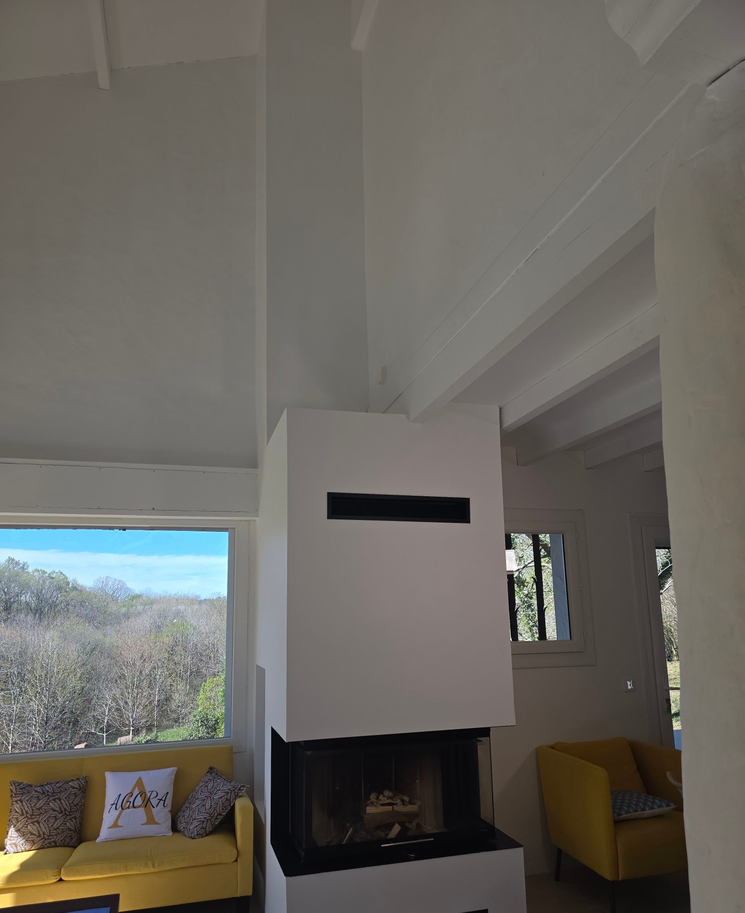 Cheminée contemporaine blanche à foyer vitré et vue sur la campagne