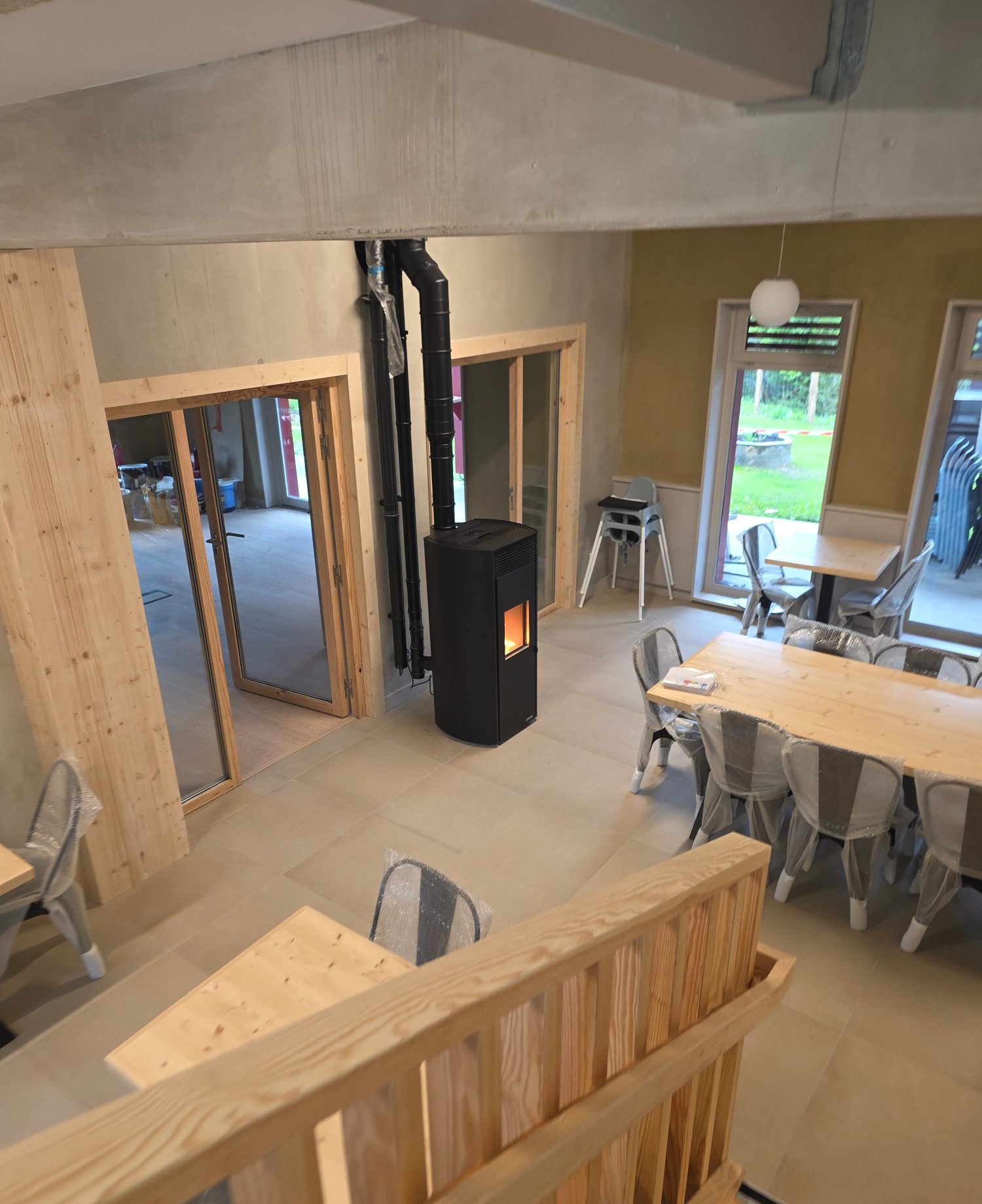 Poêle installé dans une pièce de vie ouverte avec charpente en bois