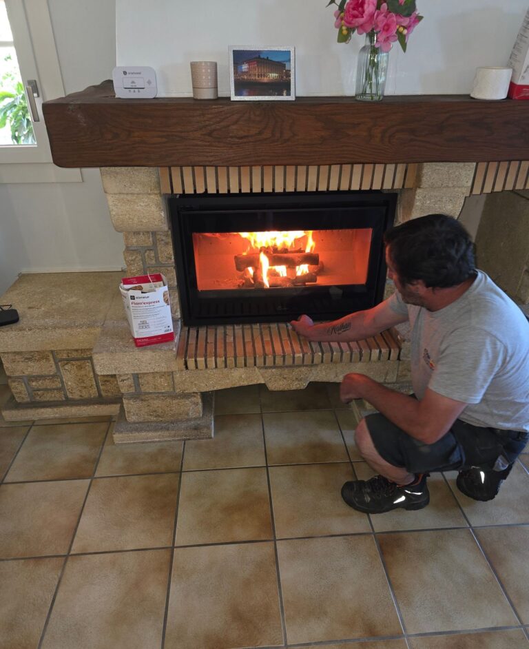 Technicien COBA Énergies contrôlant un insert à bois allumé